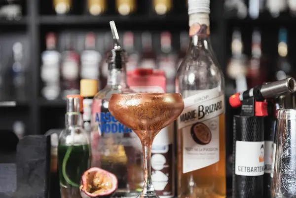 Cocktail i et kobberfarvet coupeglas på baren